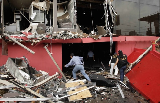 Image: Investigators walk through debris of the charred Casino Royale after a deadly arson assault in Monterrey
