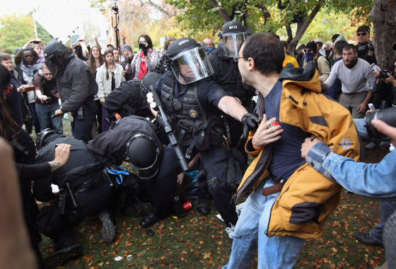 Image: Policemen in riot gear scuffle with protesters