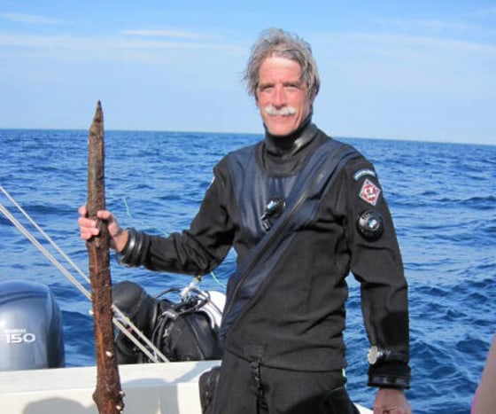 Anthropologist John O'Shea stands next to a piece of wood, thought to be a prehistoric tool, recovered from the bottom of Lake Huron.