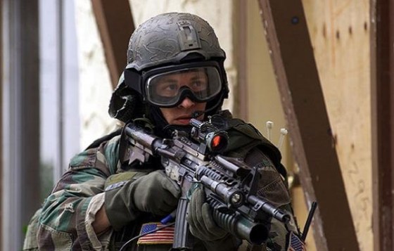 A U.S. Special Forces soldier armed with a M4A1 Carbine, fitted with an underslung M203 40mm grenade launcher, aimed with a M68 Close Combat Optic red dot sight.