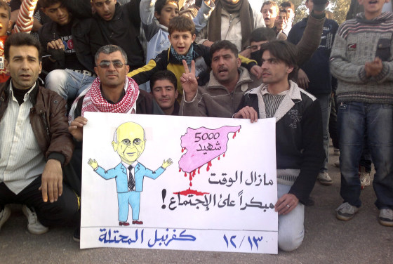Image: Demonstrators against Syria's President al-Assad hold a poster with a picture representing Arab League Secretary General Elaraby in Kafranbel near Adlb