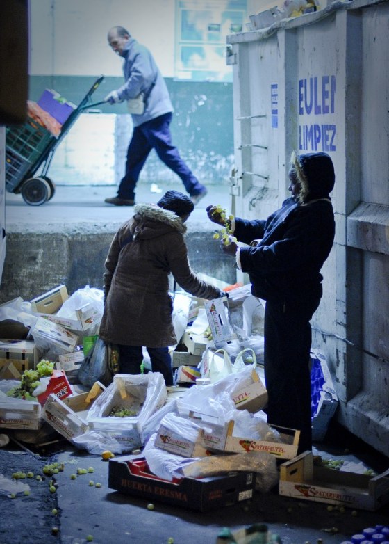 Image: Two women collect food waste beside an industrial dumpster at the main food market in Madrid.
