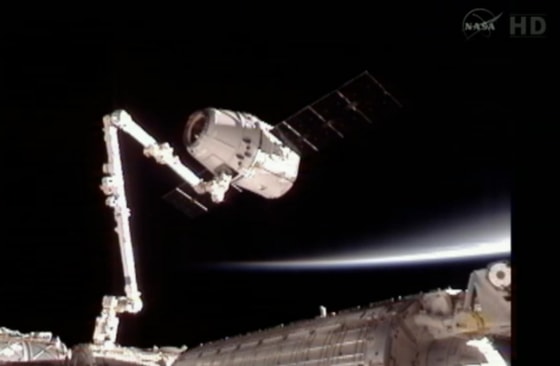 Dragon capsule attached to the Canadarm2 floats with the Earth in the background Friday.