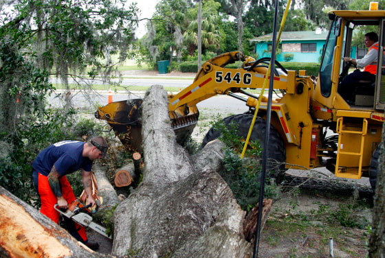 Image: A crew from the Florida Department of Transportation works to clean up the debris of a tree that fell and damaged the home of Geneva Sercey in Gainesville, Fla., in the aftermath of Tropical Storm Beryl on Monday.
