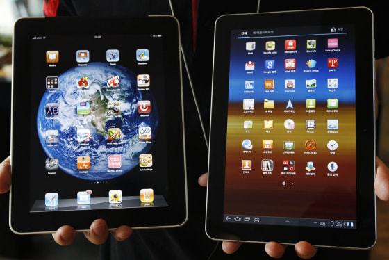 Image: File photo of an employee of South Korean mobile carrier KT holding a Samsung Electronics' Galaxy Tab 10.1 tablet and Apple Inc