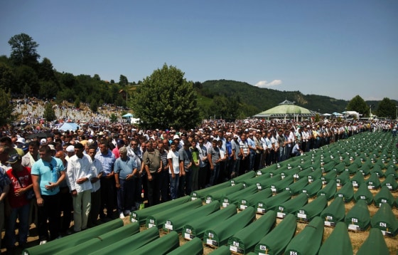 Image: Bosnian Muslims pray near coffins at the Memorial Center in Potocari during a mass burial, near Srebrenica