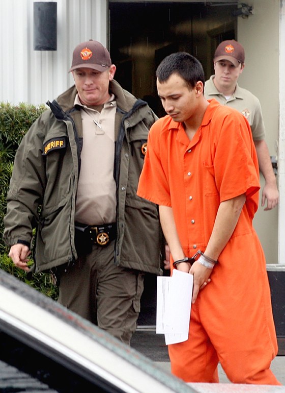 Image: U.S. Army Pvt. Isaac Aguigui, 19, is led away in handcuffs after appearing before a magistrate judge at the Long County Sheriffs Office in Ludowici, Ga.