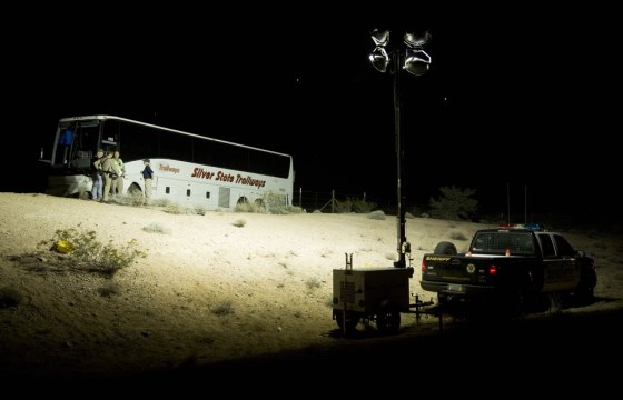 Image: Arizona Highway Patrol officers examine the exterior of a tour bus that careened off the highway and crashed