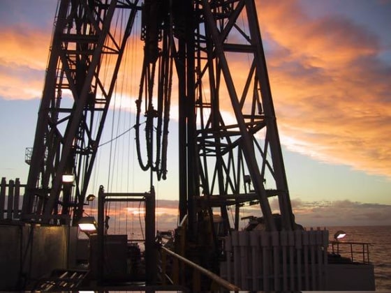 A massive drill looms above the deck of the Integrated Ocean Drilling Program ship used for the research. Scientists spent weeks in the middle of the Atlantic Ocean, boring deep into a subsea mountain to reach the remote crust where the tiny lifeforms were found.