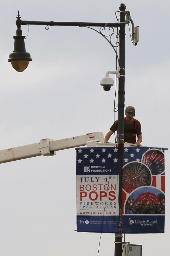 Image: A worker installs a piece of security equipment on a lamp post on a bridge over the Charles River in Boston