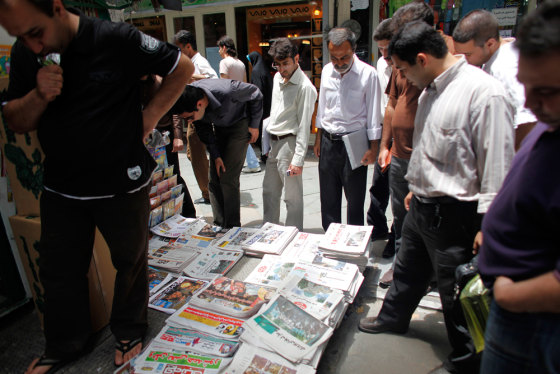 Image: Iranians read newspapers at a kiosk in central Tehran, a day after the country's presidential elections