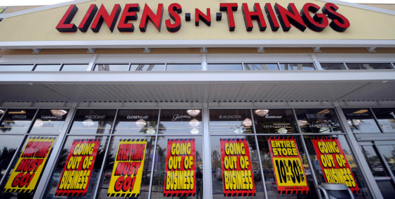 Image: Going out of business signs hang in the window of a Linens 'n Things