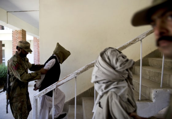 Image: Pakistani army soldiers hold suspected Taliban militants after they were presented to the media during a press briefing in a military base at Khwazakhela