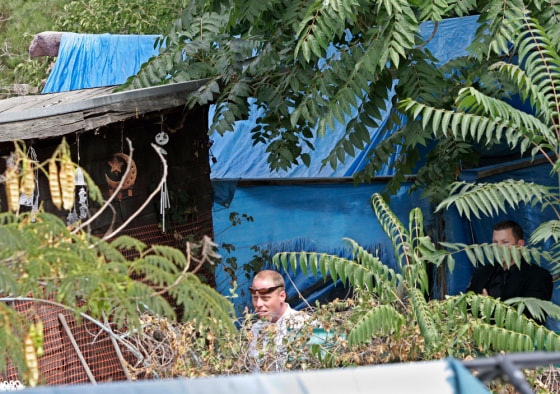 Image: Authorities walk next to shacks in the backyards of a home in Antioch, Calif.