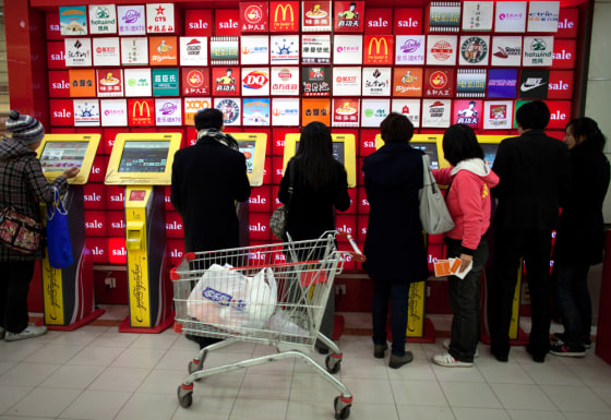 Image: People use a row of coupon machines near a supermarket entrance in Beijing, China