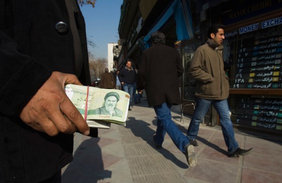 Image: File photo shows a money changer holding Iranian rial banknotes as he waits for customers in Tehran's business district