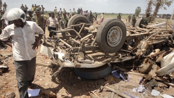 Image: A man stands next to a truck destroyed in an explosion in Batticaloa