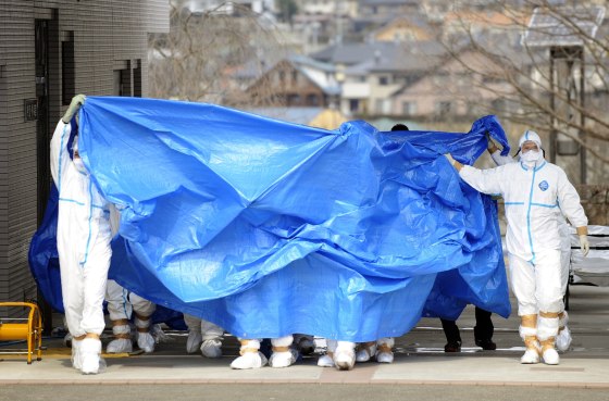 Image: Workers, who stepped into radiation-contaminated water during Thursday's operation at the Fukushima Dai-ichi nuclear plant, are shielded with tarps before receiving decontamination treatment at a hospital in Fukushima, Japan.