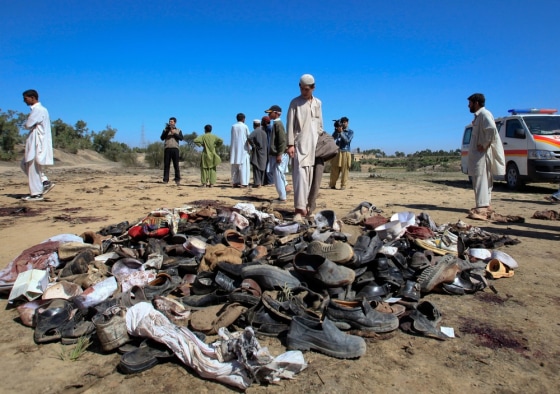 Image: A man stands next to sandals at the site of a suicide bomb attack on the outskirts of Peshawar