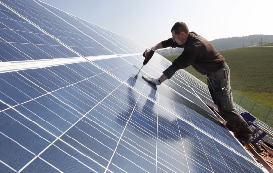Image: A worker mounts 320 square metres of solar panels on the roof of a farmstead barn in Binsham