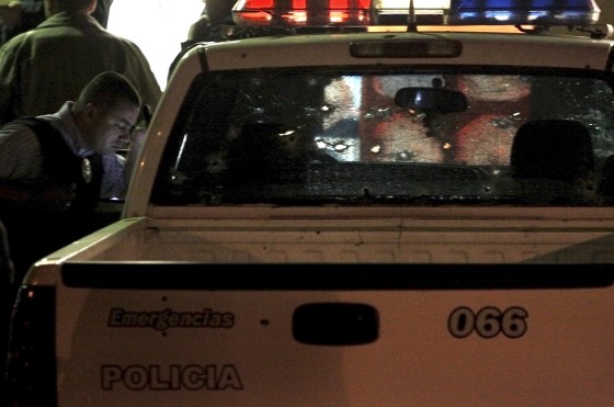 Image: Police inspect a bullet-ridden police truck at a crime scene in Tijuana