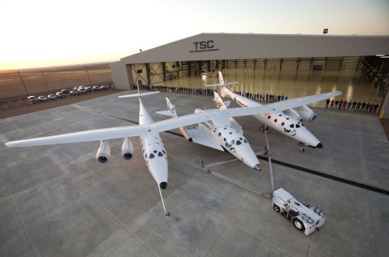 Virgin Galactic's first SpaceShipTwo suborbital spaceliner (center) is seen mated to its WhiteKnightTwo mothership in front of the "Faith" hangar at The Spaceship Company during a dedication ceremony in Mojave, Calif.