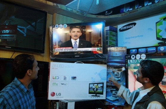 Image: Afghans listen to Obama's plan on troop withdrawl