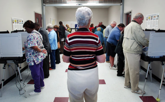 Image: A Board of Elections volunteer watches people cast their ballots
