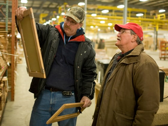 Greg Huber and Richard Eysol examine unused cabinet material that they just purchased at the auction of the Americamp RV factory.