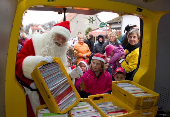 Image: A man dressed as Father Christmas carries crates with letters addressed to Santa Claus at special Christmas post office in village of Himmelpfort