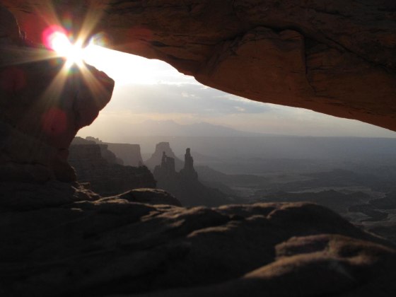 The morning sun just peeking through Mesa Arch in Canyonlands National Park, Utah.