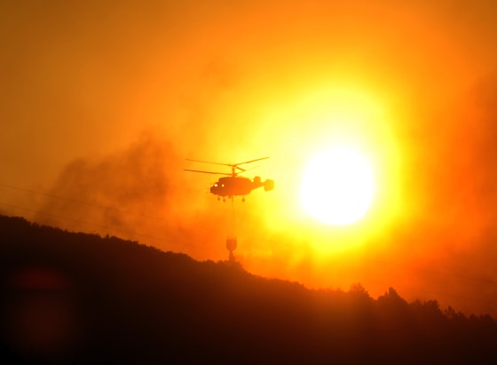 A helicopter drops water on a wildfire burning near Aliaga, Spain, on Thursday.