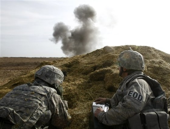 A U.S. soldier and an Explosive Ordnance Disposal expert take cover as they detonate a piece of American ordnance in the Badula Qulp area, west of Lashkar Gah in Helmand province, southern Afghanistan, Tuesday, Feb. 23.