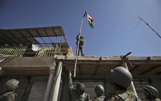 Senior Afghan Army officer instructs a soldier where to hoist an Afghan flag on a building in a market in Marjah, Afghanistan, Wednesday, Feb. 17.