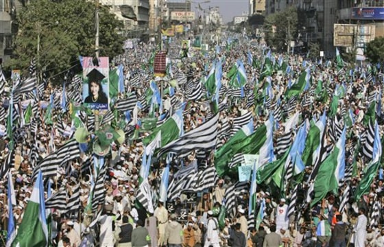 Supporters of Pakistani religious parties wave flags during a rally to protest against any attempts to modify blasphemy laws, in Karachi, Pakistan, on Sunday. Tens of thousands of demonstrators have marched in Pakistan's largest city in opposition to any change to blasphemy laws and to praise the man charged with murdering the provincial governor who opposed the legislation.