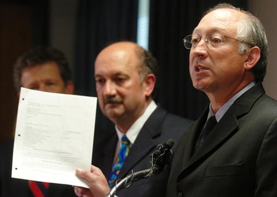 Colorado Attorney General Ken Salazar, front, holds up a copy of an agreement reached with Invesco Funds in a consumer protection case during a news conference in Denver on Tuesday.