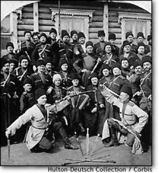 A crowd watching two of their colleagues perform a Cossack dance in Russia, circa 1870.