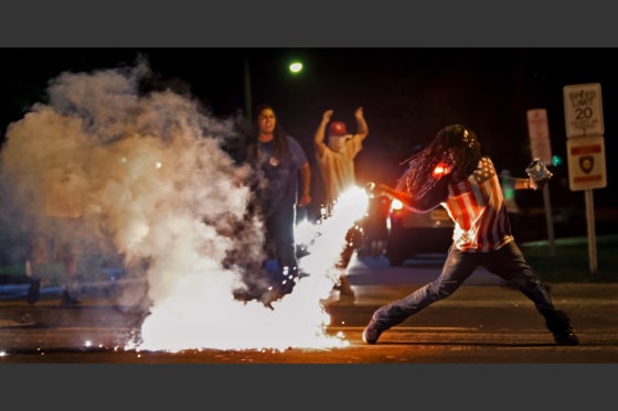 Edward Crawford returns a tear gas canister&nbsp;fired by police who were trying to disperse protesters in Ferguson, Mo., Aug. 13, 2014.&nbsp;