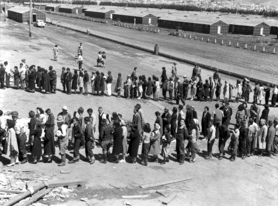 Newly arrived Japanese evacuees line up outside a mess hall at the Tanforan Assembly Center, in San Bruno, Ca., April 29, 1942. (Photo by Dorothea Lange/Interim Archives/Getty)