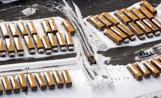 Image: A front end loader moves mounds of snow away from Columbus City School buses.