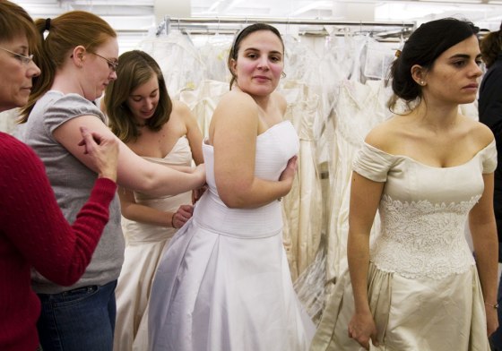 Image: Rebecca Stamilio, second from right, tries on a wedding gown during the \"Running of the Brides\" at Filene's Basement in New York