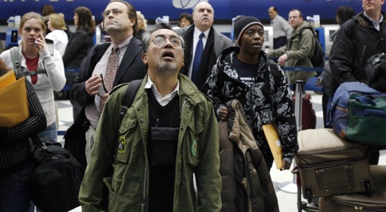 Image: Air travelers check the flight information board after flights were cancelled at Chicago's O'hare International Airport.