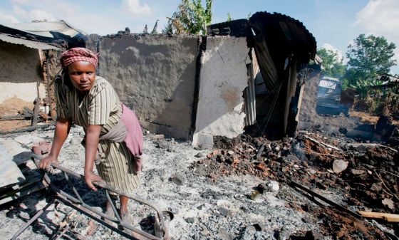 Image: A woman surveys what remains of her home that was torched in the early hours of this morning.
