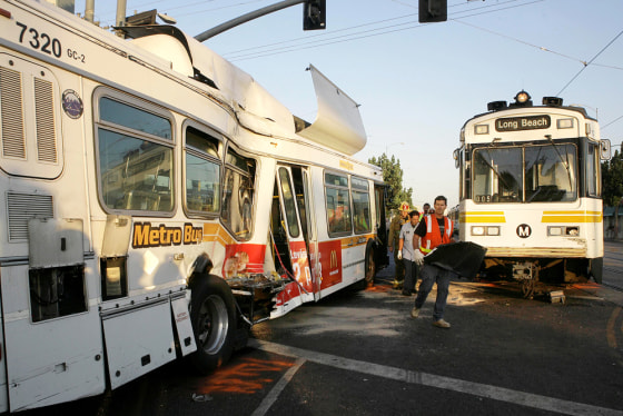 Emergency responders walk between the wreckage after a light-rail train collided with an out-of-service bus near downtown Los Angeles on Friday.