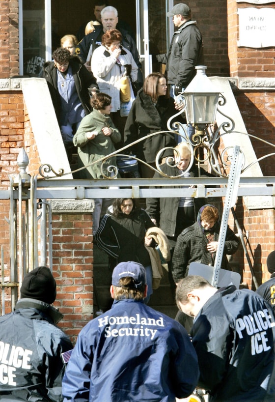 Image: Employees are escorted out after an early morning raid by federal immigration officials at the Michael Bianco Inc. textile plant in New Bedford, Mass.