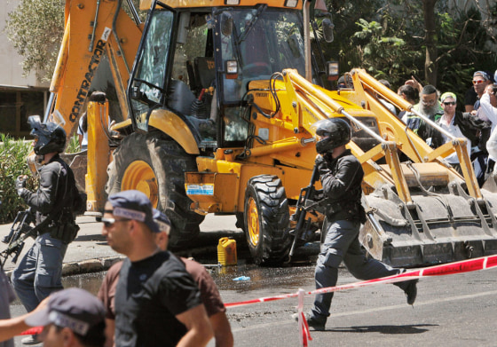 Image : Israelis run past a construction vehicle