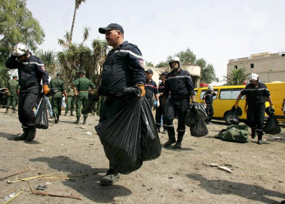 Image: Firemen carrying parts of human bodies killed in a car bomb attack near the National Gendarmerie school of Issers in the city of Boumerdes