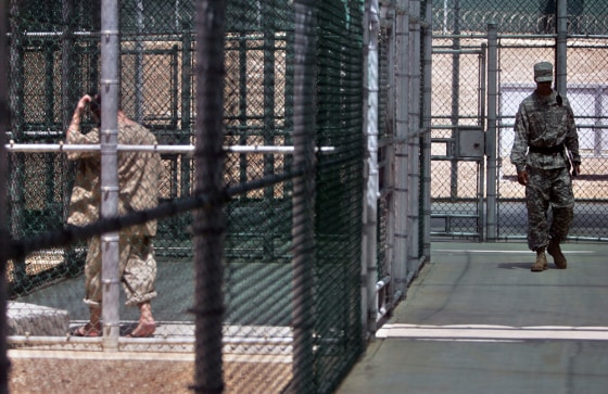 Image:  a Guantanamo detainee, left, walks in a fenced-in exercise area