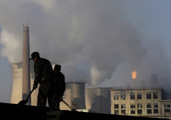 Workers in China's Hebei province on Nov. 30 shovel coal used by the power plant and chemical factory behind them. Coal-fired power plants are a major source of carbon dioxide emissions.