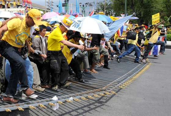 Image: Anti-government protesters break barricades during their entry into Government House in Bangkok, Thailand